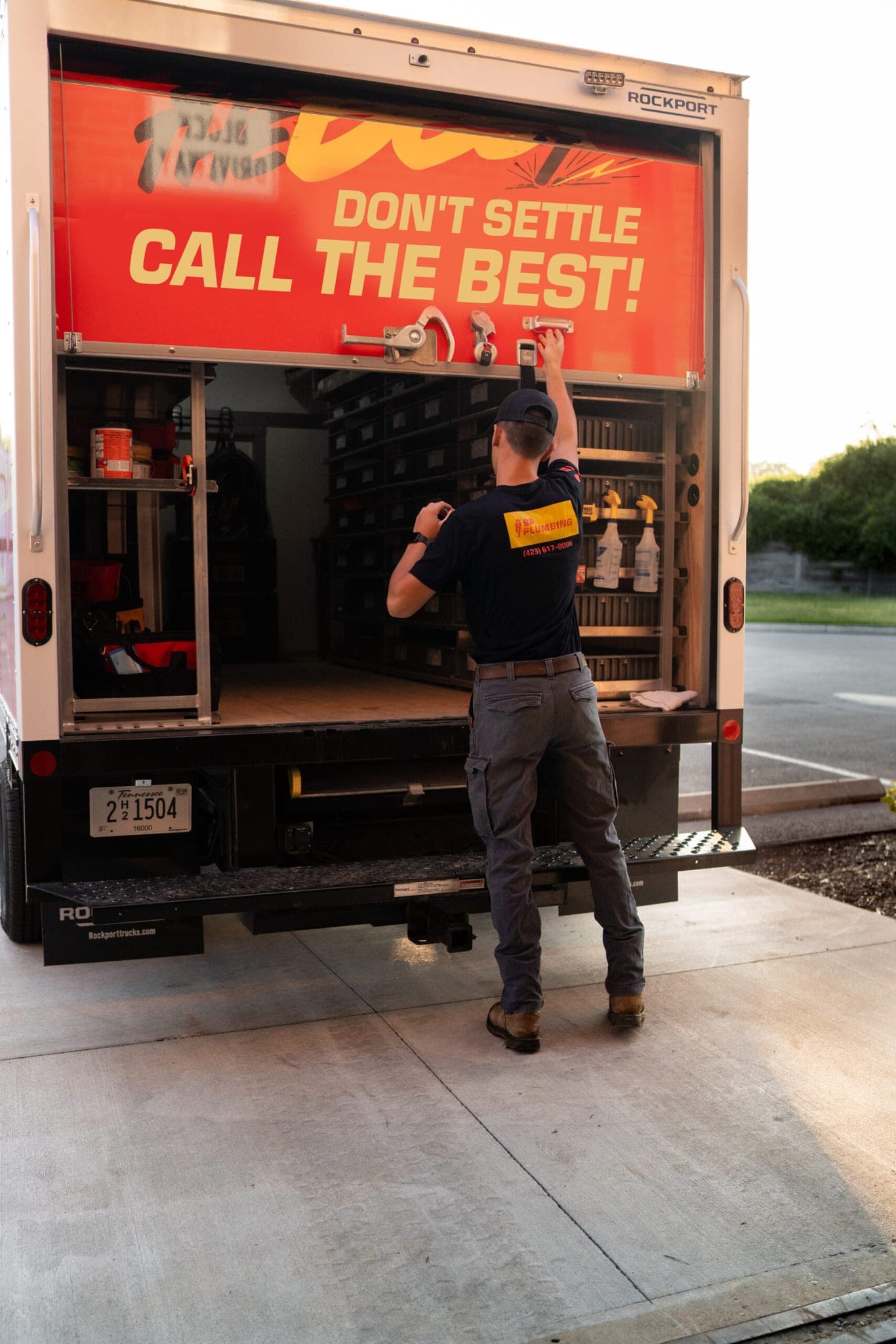 A BP Plumbing technician loading equipment from the truck's shelving